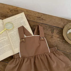 Detailaufnahme brauner Baby-Strampler mit weißer Paspelierung und Vintage-Knöpfen