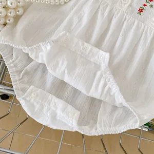 Close-up of white cotton baby bodysuit featuring floral embroidery and snap buttons