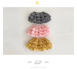 Detailed view of baby tiered ruffle shorts in black, pink and yellow gingham patterns