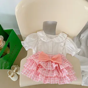 Detailed view of girls' white ruffle shirt and pink plaid layered cake skirt set