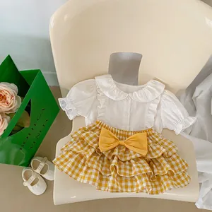 Close-up of baby girl white ruffle shirt and yellow plaid tiered cake skirt with bow