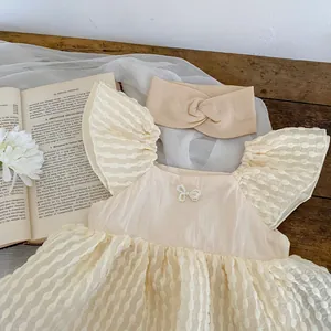 Détail d'une robe d'été pour bébé fille avec nœud en perles et bandeau assorti