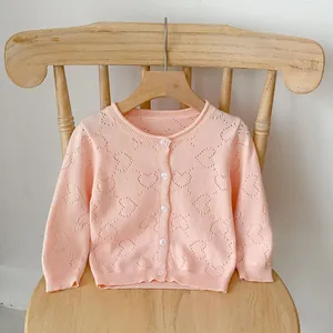 Detailed view of heart-shaped hollow knit pattern on pink baby cardigan sweater