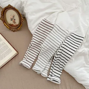 Detailed close-up of three striped cotton baby leggings in brown, grey and black