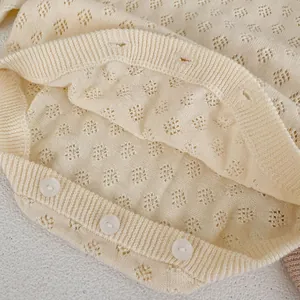 Detail of baby knit romper showing hollow diamond pattern and white round buttons