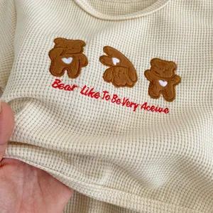 Macro detail of breathable waffle fabric texture with cute bear embroidery on baby top