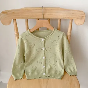 Close-up of mint green knitted baby cardigan with hollow heart pattern and white buttons