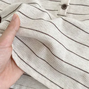 Dettaglio del tessuto a nido d'ape per neonati con strisce marroni e cuciture