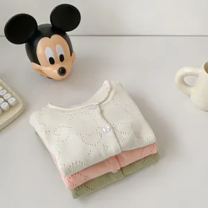 Flat lay of stacked knit cardigans in beige, pink and green with heart pointelle