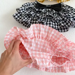 Detail of baby gingham tiered skirt pants showing the built-in diaper cover and bow