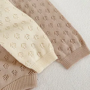 Detail of pointelle hollow knit texture and ribbed cuffs on baby cotton sweaters