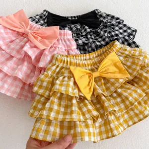 Detail of ruffled plaid baby skort showing layered lace cake skirt and bow in multi colors
