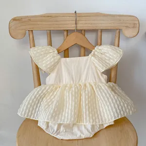 Détail d'une barboteuse à volants crème pour bébé fille suspendue sur une chaise