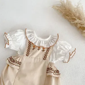 Detail of floral embroidery on baby girl bubble sleeve top and beige suspender set