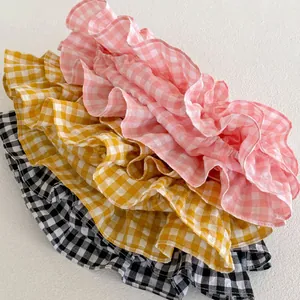Detailed view of ruffled gingham fabrics in pink, yellow, and black for baby girls