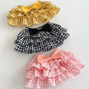 Detailed view of layered ruffle plaid baby skirts with decorative bow in three colors