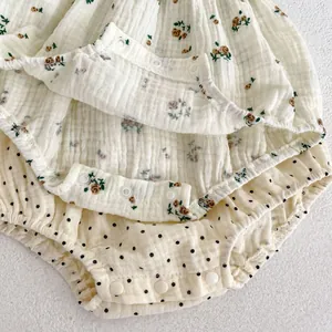 Detail of floral and polka dot muslin baby rompers with convenient bottom snap fasteners