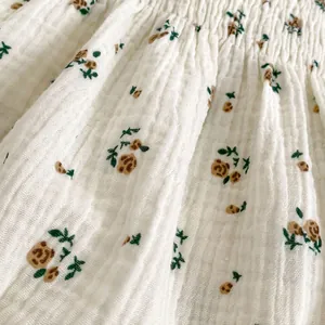 Detail of floral baby girl romper with yellow rose print and delicate smocked stitching