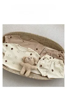 Flat lay of baby waffle cotton short sets with bear print in a cozy woven basket