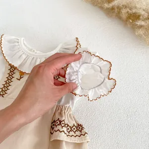 Detailed view of baby floral embroidery romper with matching ruffle headband accessory