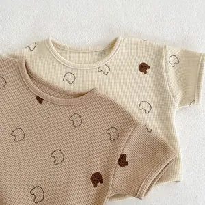 Detailed close-up of baby waffle cotton set featuring cute bear prints in cream and brown