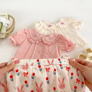 Dettaglio gonna a fiori e camicia neonata con ricamo a coniglio su colletto Peter Pan
