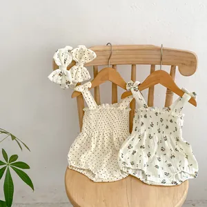 Summer floral and polka dot baby rompers with matching bow headbands on wooden hangers
