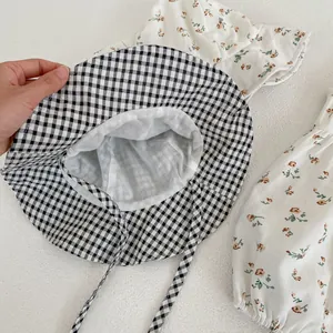 Détail d'une barboteuse fleurie pour bébé avec chapeau vichy assorti et doublure douce