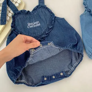Infant denim romper with heart embroidery and ruffles, featuring bottom snap buttons