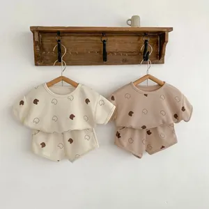 Detail view of cotton waffle knit baby sets with bear prints in cream and earth tones