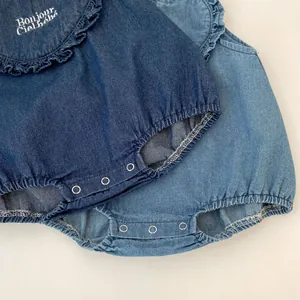 Detail of baby denim romper featuring ruffle collar, embroidery and metal crotch snaps