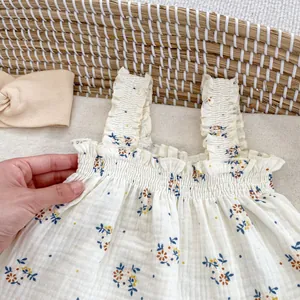 Dettaglio top neonata a fiori in mussola traspirante in una culla di vimini intrecciata