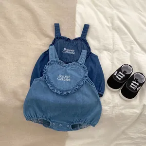 Detail of infant denim rompers with heart ruffle pocket and embroidered lettering