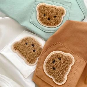 Close-up of baby vest pocket featuring a plush 3D cartoon bear embroidery patch