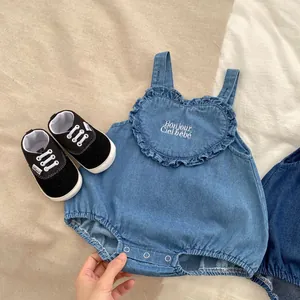 Detail of light blue denim baby bodysuit featuring heart ruffles and Bonjour embroidery