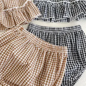 Detail view of cotton gingham baby girl sets showing ruffled edges and elastic waistbands