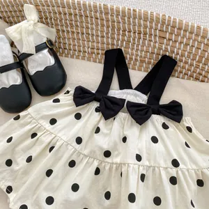 Close-up of baby romper with black polka dots and shoulder bows on breathable cotton fabric