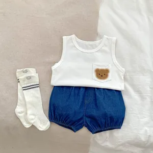 Flat lay of baby summer set with bear vest, denim shorts and smiley face socks