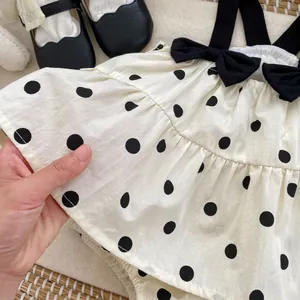 Detailed close-up of breathable polka dot fabric and black bow on a baby bodysuit