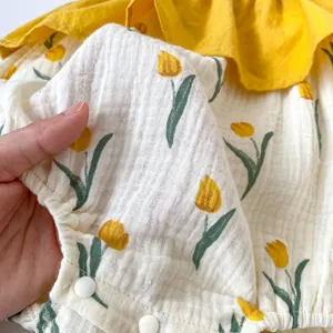 Détail de barboteuse bébé avec imprimé tulipes, volants et boutons-pression
