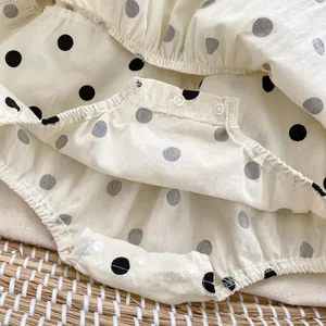 Detailed close-up of crotch snaps on a cream polka dot baby bodysuit made of cotton