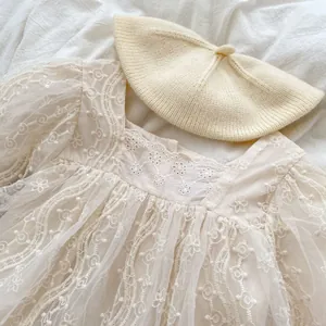 Dettaglio del body in pizzo per neonati con rete ricamata e set berretto in maglia