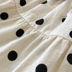 Close-up of baby girl polka dot romper with detailed cotton fabric and soft pleats