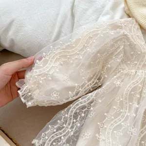 Dettaglio delle maniche a lanterna in pizzo ricamato su un abito body neonata