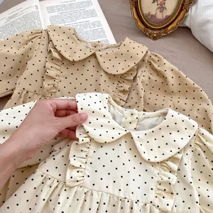Detail of Peter Pan collar and ruffle trim on polka dot corduroy baby bodysuit