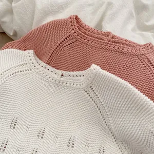 Detail van gebreide baby-trui met opengewerkte patronen en zachte katoen-textuur van de stof