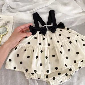 Detail of baby polka dot romper showing bow straps and snap button closure bottom