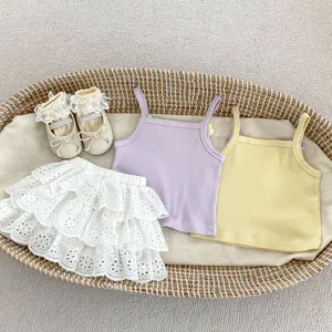 Detalle de camisetas de tirantes para bebé con falda de encaje y zapatos con lazo