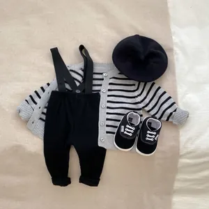 Flat lay of baby striped cardigan, ribbed overalls, beret, and sneakers in size 12-18m