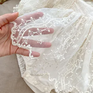 Pagliaccetto bianco neonata con ricami floreali e dettaglio in tulle a balze